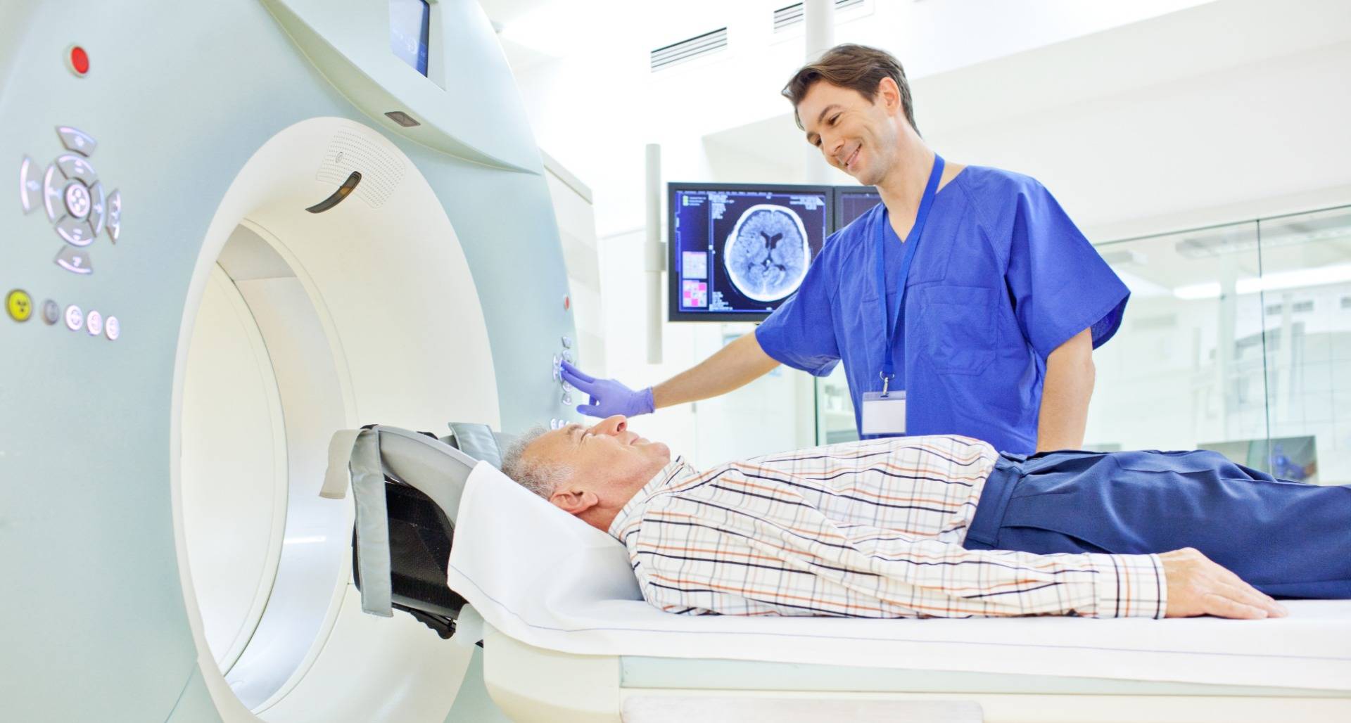 Health-care professional guiding man through medical imaging procedure